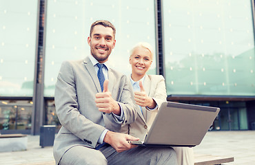 Image showing smiling businesspeople with laptop outdoors