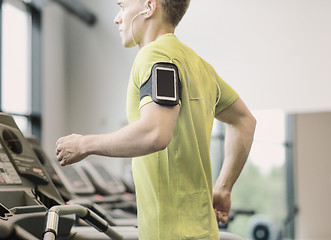 Image showing man with smartphone exercising on treadmill in gym