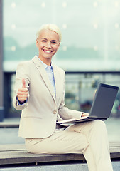 Image showing smiling businesswoman working with laptop outdoors