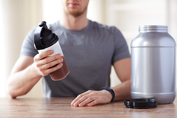 Image showing close up of man with protein shake bottle and jar