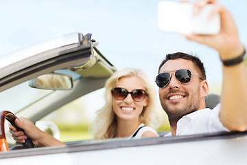 Image showing happy couple in car taking selfie with smartphone