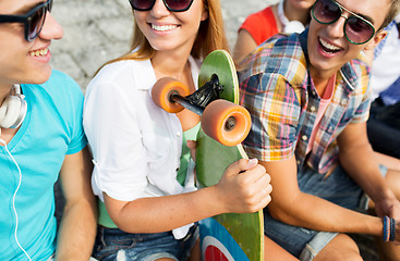 Image showing close up of happy friends with longboard on street
