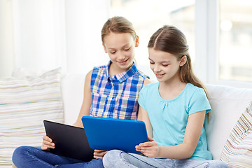 Image showing happy girls with tablet pc sitting on sofa at home