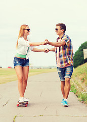 Image showing smiling couple with skateboard outdoors