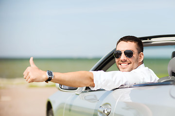 Image showing happy man driving car and showing thumbs up
