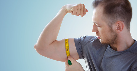 Image showing close up of male hands with tape measuring bicep