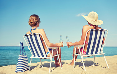 Image showing happy women sunbathing in lounges on beach