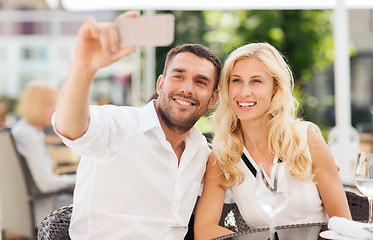 Image showing happy couple taking selfie with smatphone at cafe