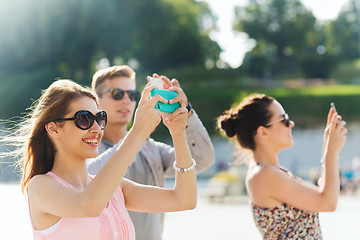 Image showing smiling friends with smartphone taking picture