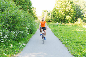 Image showing happy young man riding bicycle outdoors