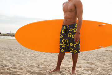 Image showing close up of young man with surfboard on beach