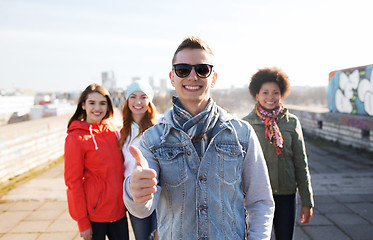 Image showing happy teenage friends showing thumbs up on street