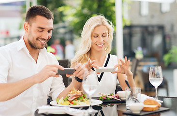 Image showing happy couple with smatphone photographing food