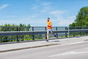 Image showing smiling young man running at summer seaside