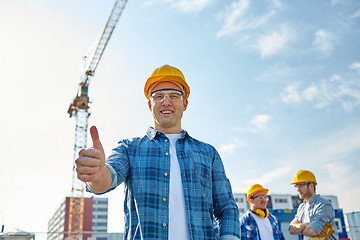 Image showing group of smiling builders in hardhats outdoors