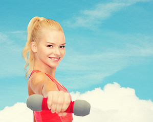 Image showing smiling beautiful sporty woman with dumbbell