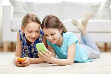 Image showing happy girls with smartphones lying on floor