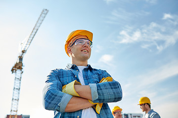 Image showing group of smiling builders in hardhats outdoors