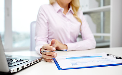 Image showing smiling businesswoman reading papers in office