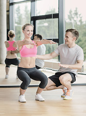 Image showing smiling woman with male trainer exercising in gym