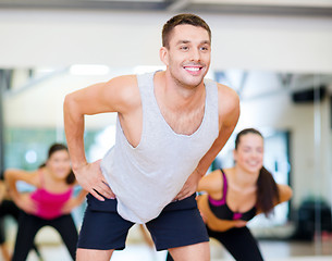 Image showing smiling male trainer working out in the gym