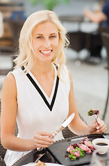 Image showing happy woman eating dinner at restaurant terrace