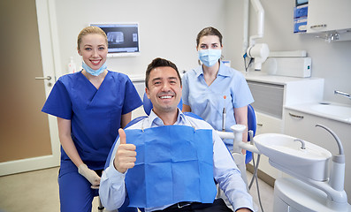 Image showing happy female dentists with man patient at clinic