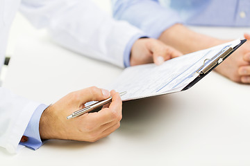 Image showing close up of male doctor and patient with clipboard