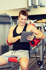 Image showing smiling young man with tablet pc computer in gym