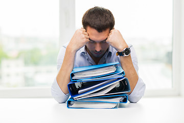 Image showing sad businessman with stack of folders at office