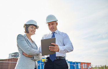 Image showing happy builders in hardhats with tablet pc outdoors