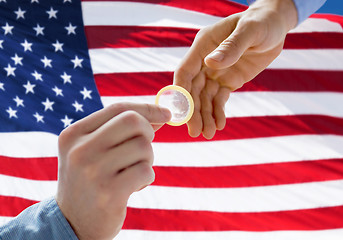 Image showing close up of male gay couple hands giving condom