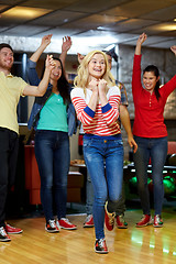 Image showing happy young woman throwing ball in bowling club