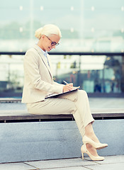 Image showing young smiling businesswoman with notepad outdoors