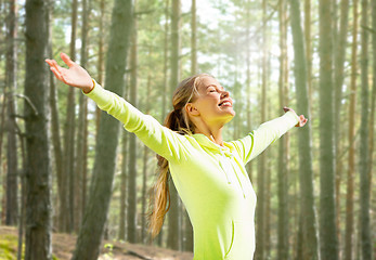 Image showing happy woman in sport clothes raising hands