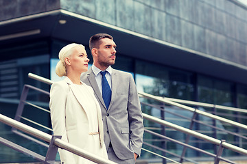 Image showing serious businessmen standing over office building