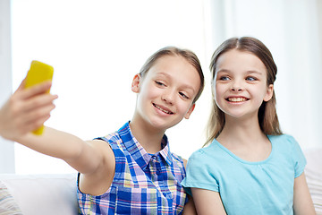 Image showing happy girls with smartphone taking selfie at home