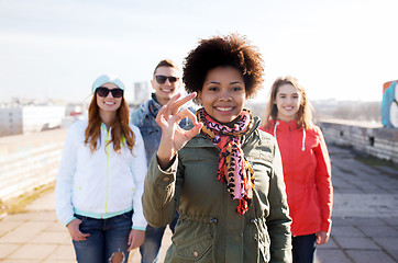 Image showing happy teenage friends showing ok sign on street