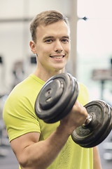 Image showing smiling man with dumbbell in gym