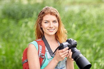 Image showing happy woman with backpack and camera outdoors
