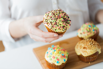 Image showing close up of woman with glazed cupcakes or muffins