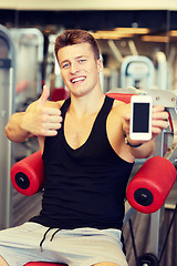 Image showing smiling young man with smartphone in gym