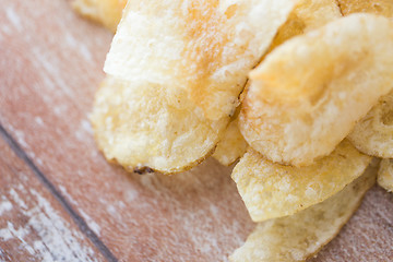 Image showing close up of crunchy potato crisps on wooden table