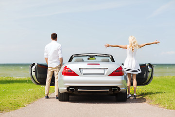 Image showing happy man and woman near cabriolet car at sea