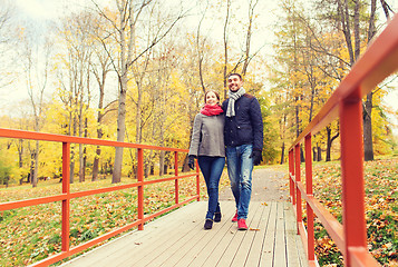 Image showing smiling couple hugging on bridge in autumn park