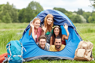 Image showing happy friends with backpacks in tent at camping