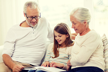 Image showing smiling family with book at home