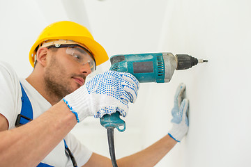 Image showing builder in hardhat with drill perforating wall