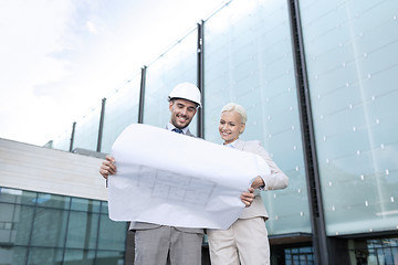 Image showing smiling businessmen with blueprint and helmets