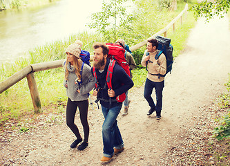 Image showing group of smiling friends with backpacks hiking